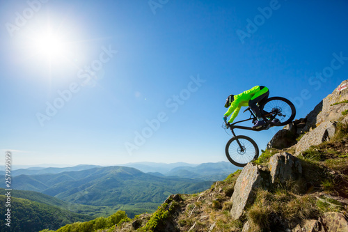                     A man is riding bicycle  on the background of mountains and blue sky. Beautiful summer day. 