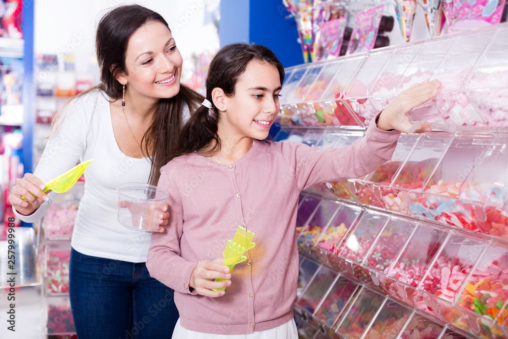 Smiling woman and girl buying marmalade in the candy store