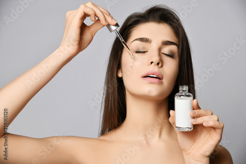 Young woman with eyes closed with pleasure of renewal drops of a crystal clear cosmetic for skin from pipette on her face
