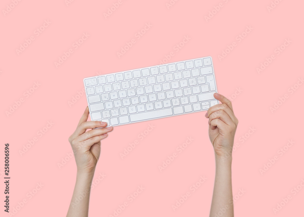 Raising hands with keyboard on pink background Raising hands with keyboard on pink background