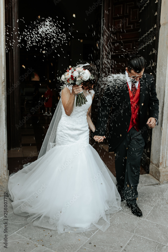 People throw rice on newlyweds walking out of the church