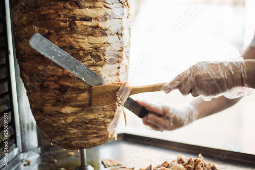 cook chapati. Preparation of traditional shawarma and shawarma (doner kebab). Spit with meat cuts a man Arab.