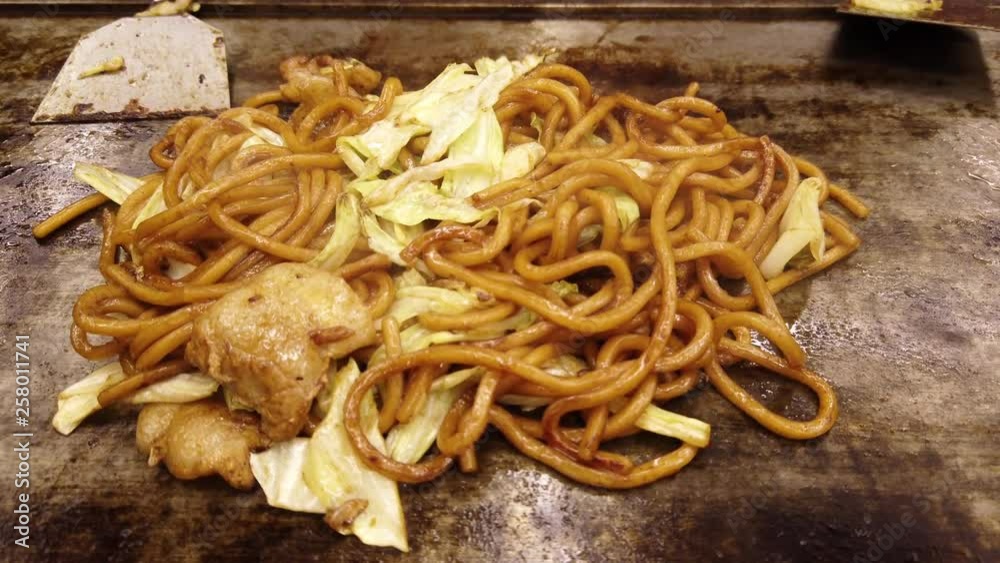 4K Video selective focus close up stabilize shot of cooked fresh hot fried japanese noodle yakisoba with cabbage, sauce and pork meat on iron frying pan or iron plate in restaurant 4K Video selective focus close up stabilize shot of cooked fresh hot fried japanese noodle yakisoba with cabbage, sauce and pork meat on iron frying pan or iron plate in restaurant