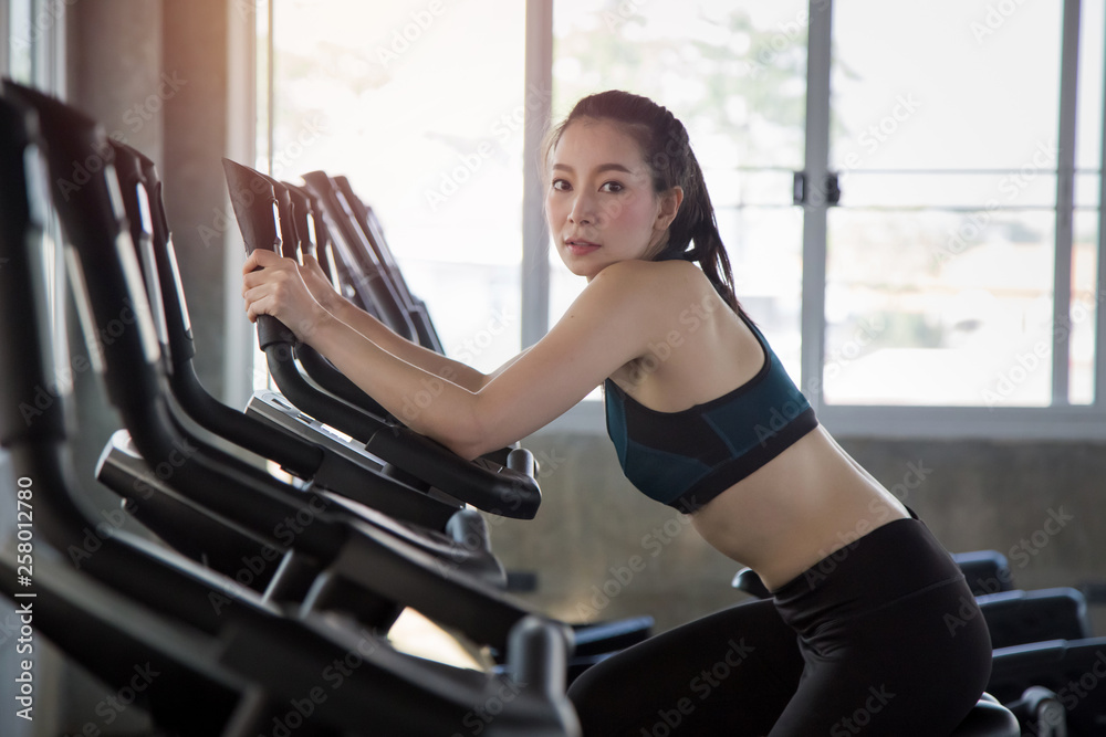 Beautiful Asian woman use exercise bike for workout at gym.