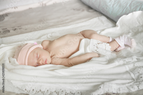 sleeping naked newborn baby girl on a white blanket