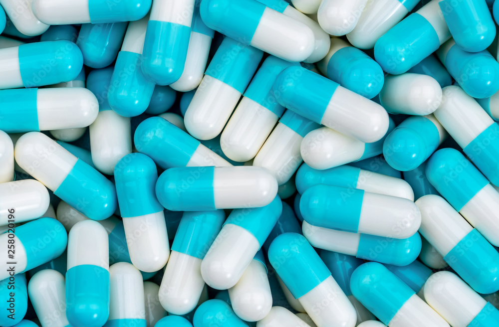 Top view pile of blue and white antibiotic capsule pills texture. Pharmaceutical production. Global healthcare. Antibiotics drug resistance. Antimicrobial capsule pills. Pharmaceutical industry.