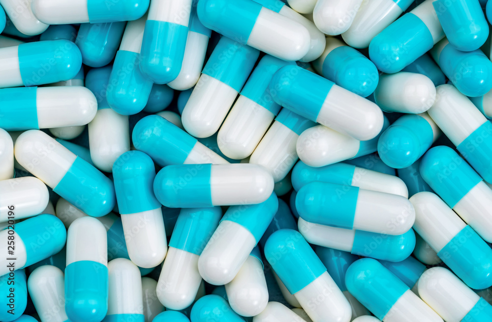 Top view pile of blue and white antibiotic capsule pills texture. Pharmaceutical production. Global healthcare. Antibiotics drug resistance. Antimicrobial capsule pills. Pharmaceutical industry. Top view pile of blue and white antibiotic capsule pills texture. Pharmaceutical production. Global healthcare. Antibiotics drug resistance. Antimicrobial capsule pills. Pharmaceutical industry.