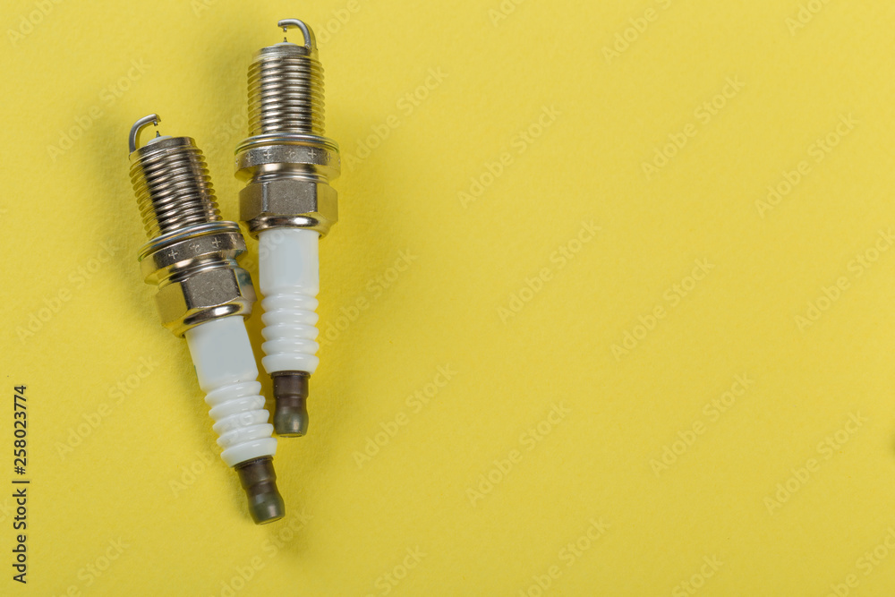 Φωτογραφία A set of new spark plugs a yellow background.