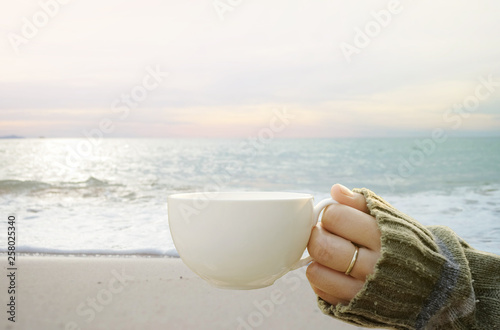 young woman enjoying cup of coffee on the beach