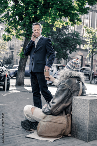 Busy short-haired man having phone call and throwing money