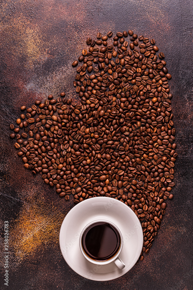 Naklejka premium A cup of coffee and coffee beans poured in the form of a heart