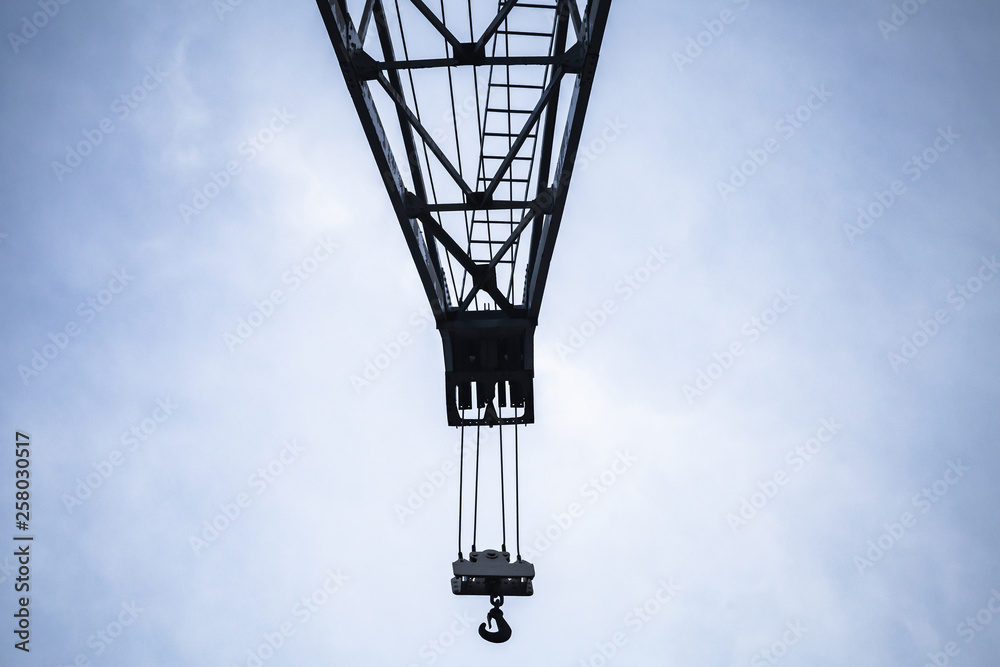 Crane boom with hook under blue sky Crane boom with hook under blue sky