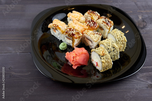 Sushi rolls with ginger and wasabi on a black plate