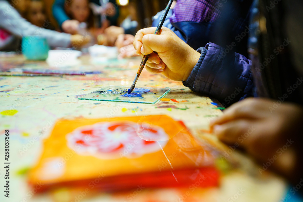 Fototapeta premium Child painted on a glass. traditional glass painting. child hand with nail polish. child painting a flower, stained glass. 