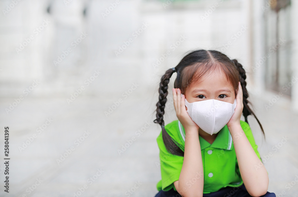 Asian child girl wearing a protection mask while outside to against PM 2.5 air pollution with pointing up in Bangkok city. Thailand. Asian child girl wearing a protection mask while outside to against PM 2.5 air pollution with pointing up in Bangkok city. Thailand.