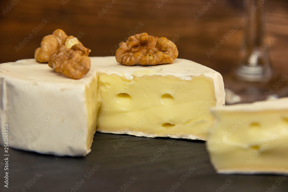 Camembert chopped on a dark background with nuts