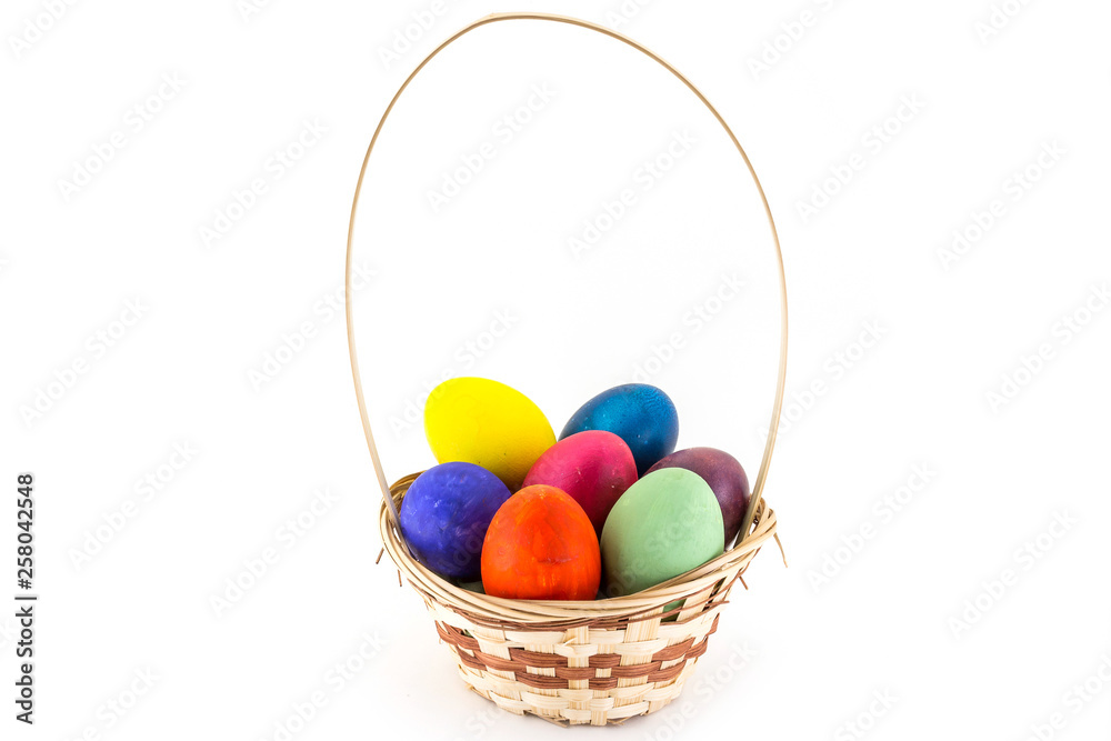 Colorfull Easter eggs in wicker basket isolated on white background