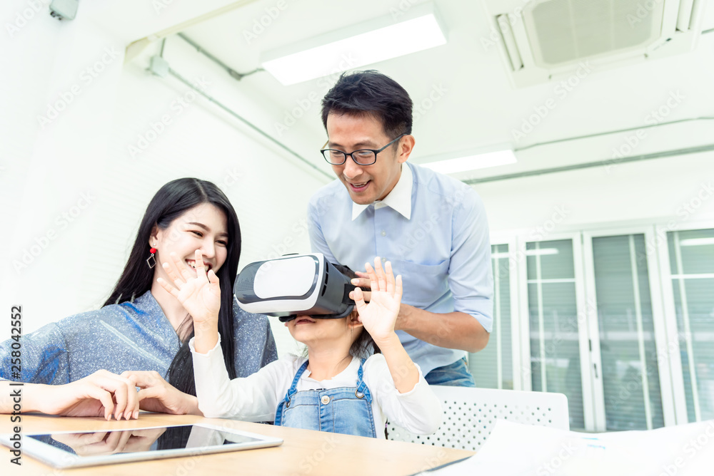 Fototapeta premium Happiness family leisure time in living room togetherness .Asian family having good time at home sitting on desk, playing ,drawing gadget technology media, little girl having fun. relax time concept.