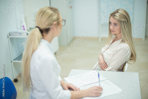 Young pregnant woman taking consultation at doctor s office. Beautiful gynecologist and young pregnant woman meet in hospital