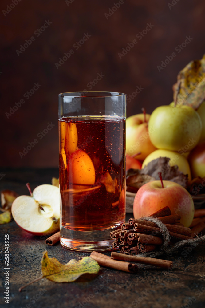 Glass of apple juice or cider with juicy apples and cinnamon sticks. Glass of apple juice or cider with juicy apples and cinnamon sticks.