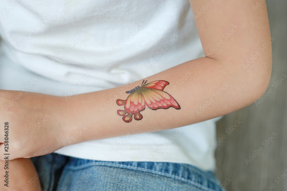 Obraz premium Close-up little child girl with butterfly tattoo sticker on hand, Dress up tattoos.