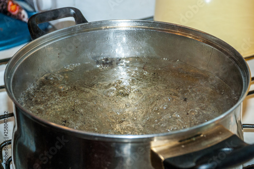 Boiling water for spaghetti or soup in a stainless steel pan on the kitchen stove at home