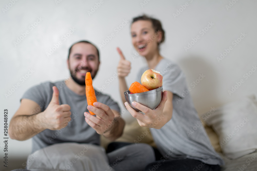 Happy couple holds a plate of vegetables in their hands. White background. Happy couple holds a plate of vegetables in their hands. White background.