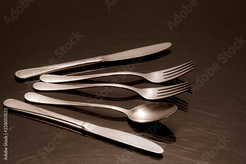Two silver knives, two forks and a spoon are on the table