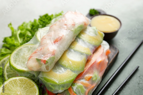 Board with tasty spring rolls on table