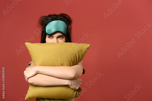 Obraz na plátně Sleepy young woman with mask and pillow on color background