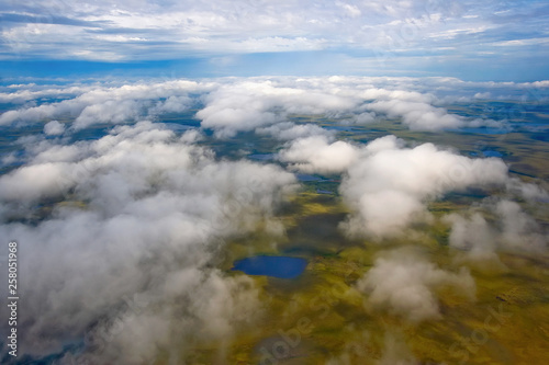 Flying in the sky above the clouds. Aerial photography. View of the tundra with small lakes. Arctic nature. Chukotka, Siberia, Far East of Russia.