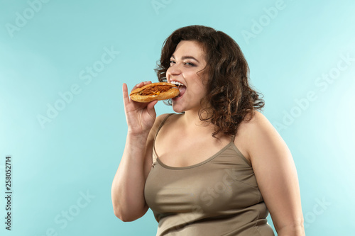 Overweight woman with sandwich on color background