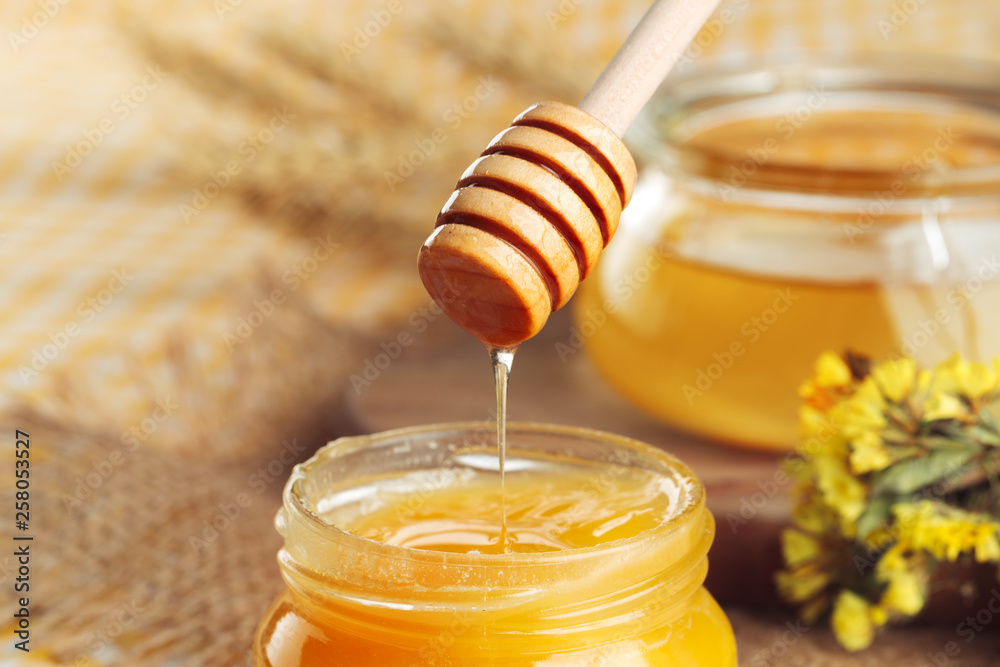 Honey background. Sweet honey in glass jar on wooden background. Honey background. Sweet honey in glass jar on wooden background.