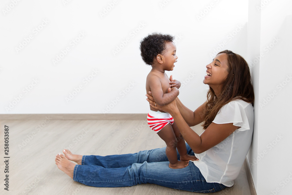 Mother and toddler boy laughing together on wood floor Mother and toddler boy laughing together on wood floor