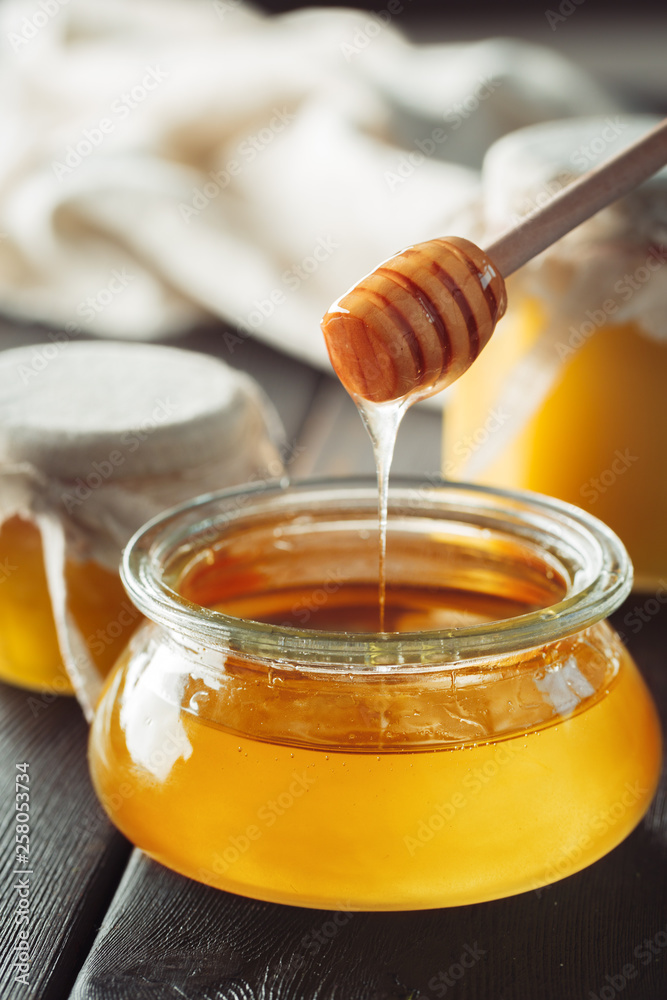 Honey background. Sweet honey in glass jar on wooden background. Honey background. Sweet honey in glass jar on wooden background.
