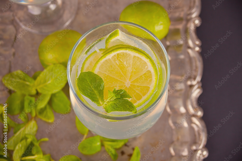 Fototapeta premium Lemonade or mojito cocktail with lemon and mint, cold refreshing drink or beverage with ice
