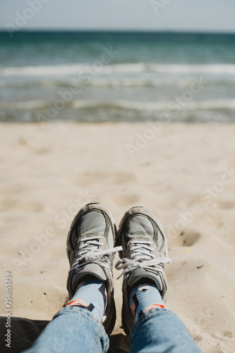 lifestyle picture of sneakers on the beach with white sand and seaview
