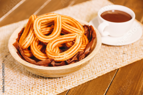 spanish fritters served on a wooden table with a cup of hot chocolate