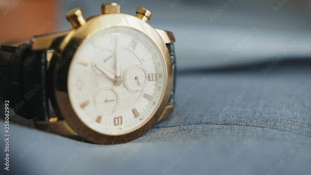 Timelapse of moving, rotating minute and second hands in wristwatch with strap lying on blue fabric surface Timelapse of moving, rotating minute and second hands in wristwatch with strap lying on blue fabric surface