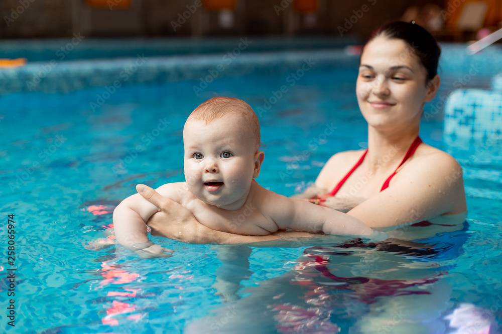 baby with mom learns to swim in the pool