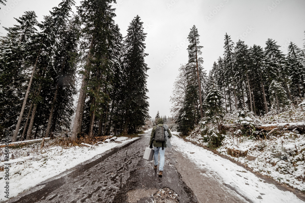 tourist man with a backpack going through a snowy forest. wide angle