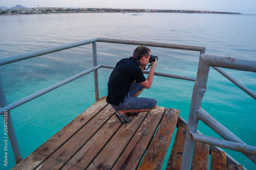 man s photographing sea from a pier
