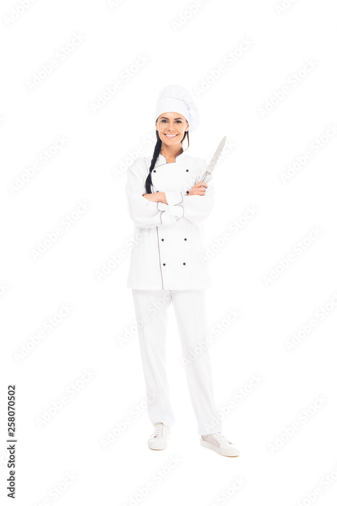 Full length view of smiling chef in uniform holding knife with crossed arms isolated on white Full length view of smiling chef in uniform holding knife with crossed arms isolated on white