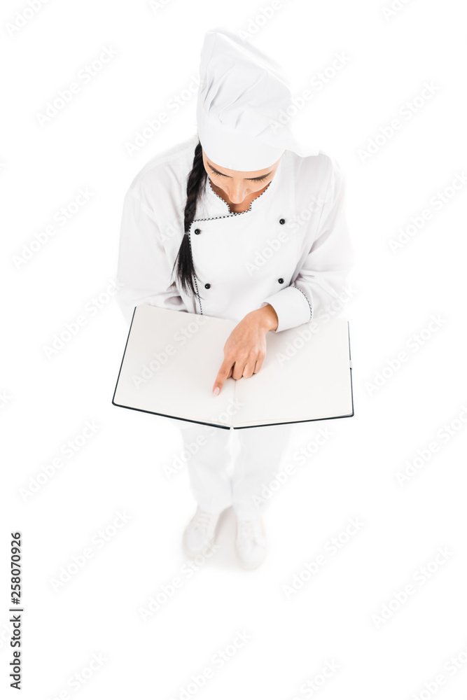 Brunette chef in uniform reading book isolated on white Brunette chef in uniform reading book isolated on white