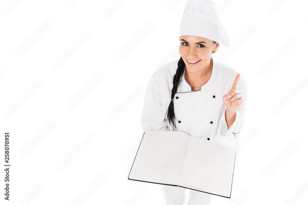 Smiling chef holding open book and showing idea gesture isolated on white Smiling chef holding open book and showing idea gesture isolated on white