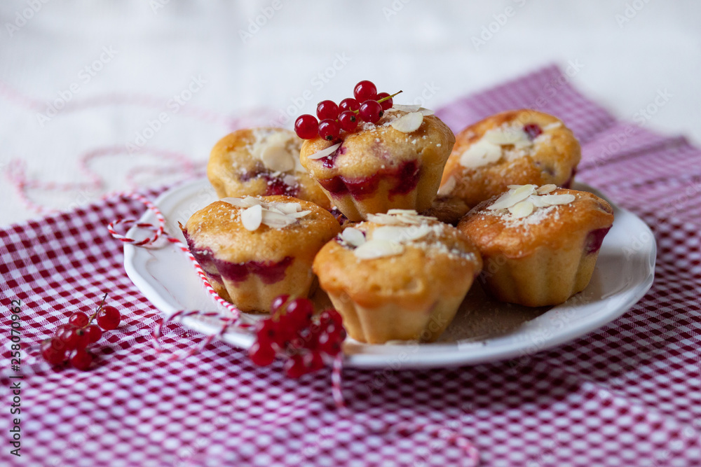 Delicious homemade raspberry cupcakes for a birthday party. Decorated with berries and almond, served on a red festive napkin. White plate. Daylight Delicious homemade raspberry cupcakes for a birthday party. Decorated with berries and almond, served on a red festive napkin. White plate. Daylight