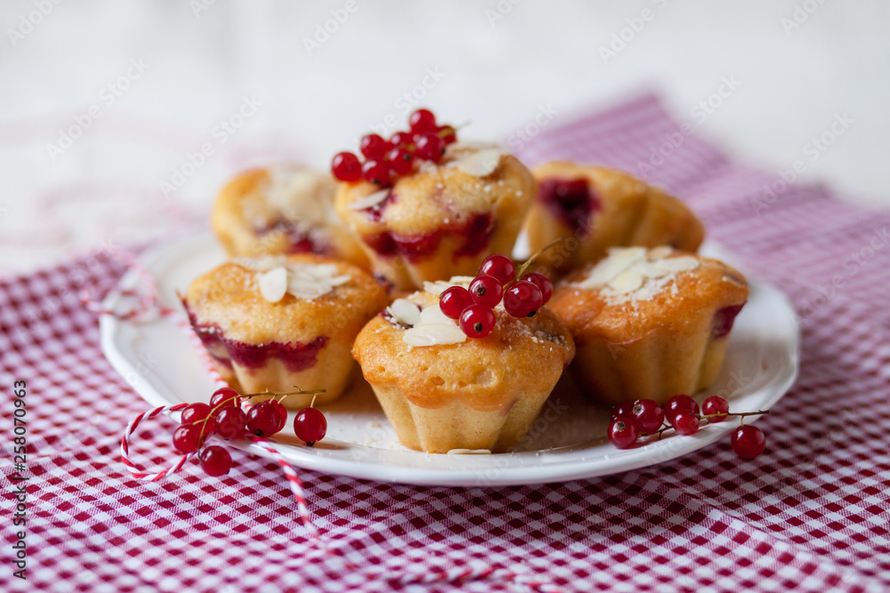 Delicious homemade raspberry cupcakes for a birthday party. Decorated with berries and almond, served on a red festive napkin. White plate. Daylight