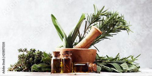 Fresh herbs from the garden and the different types of oils for massage and aromatherapy on table photo