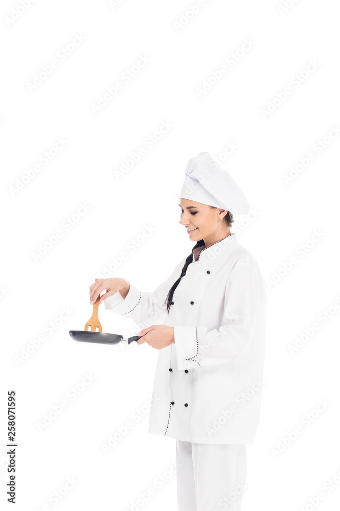 Chef in hat holding frying pan and wooden kitchen spatula isolated on white