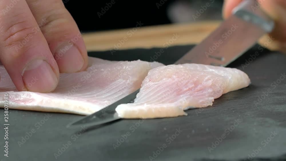 The cook fillets trout fish. filleted on black stone The cook fillets trout fish. filleted on black stone